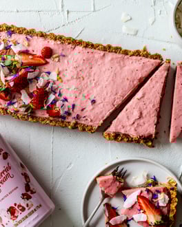 Tarte mit Erdbeer-creme gefüllt und Erdbeeren, Blüten und Kokoschips dekoriert.