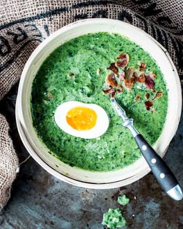 Eine Schale mit cremigem Rahmspinat, Ei und knusprigem Bacon-Topping.