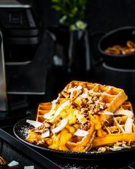Kürbiswaffeln mit gerösteten Pekannüssen aus dem KRUPS Waffeleisen Professional, auf dunklem Teller vor dunklem Hintergrund.