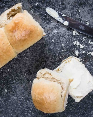 Selbstgemachte Brioche Buns auf grauem Untergrund mit Messer