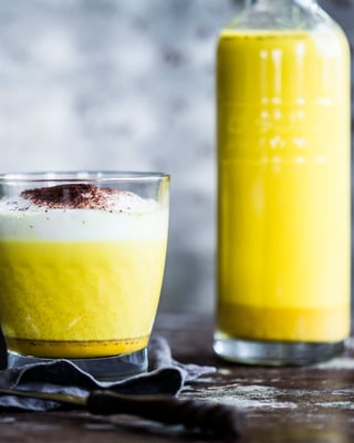 Goldene Milch in Glas und Karaffe gefüllt von der Seite