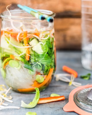 Vegane Pho-Suppe im Weckglas mit Essstäbchen, Sprossen und einem Löffel nebenliegend