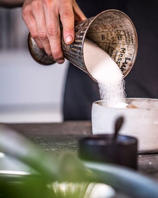 Zucker wird in eine Schüssel geschüttet