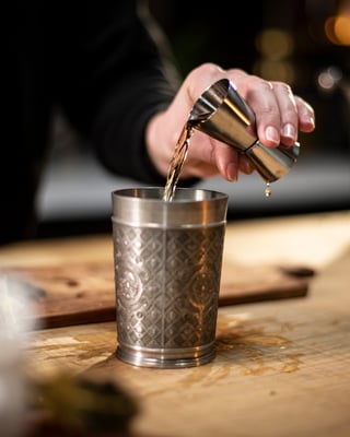 Zutaten mit dem Jigger in den Becher geben