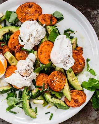 Avocado-Süßkartoffel-Salat mit pochiertem Ei auf einem Teller serviert.