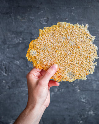 riesengroßer Parmesanchip wird von Hand gehalten