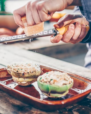 Gefüllte Artischockenhälften werden mit Parmesan bestreut, bevor sie gegrillt werden.