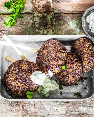 Eine Blechdose mit 4 Quinoa-Bratlingen mit Dip auf einem Holzuntergrund