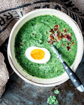 Eine Schale mit cremigem Rahmspinat, Ei und knusprigem Bacon-Topping.