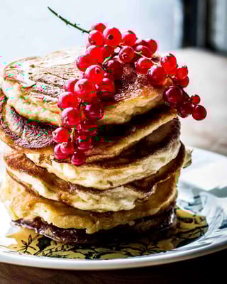 Pancakes wie aus den Staaten, mit Buttermilch und Johannisbeeren auf einem Teller gestapelt