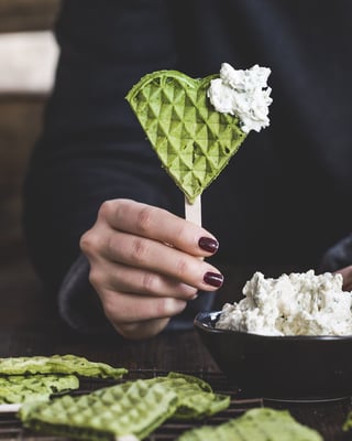 Grüne Spinatwaffeln an einem Holzstiel mit hellem Dip.