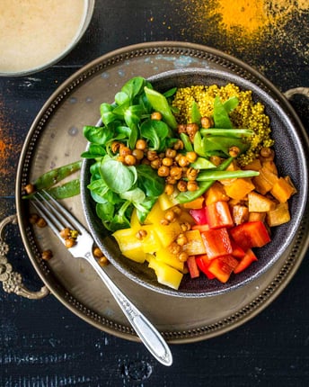 Buddha Bowl mit Quinoa und gerösteten Kichererbsen auf einem orientalischen Tablett