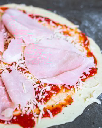 Schinken wird auf Pizza Prosciutto verteilt