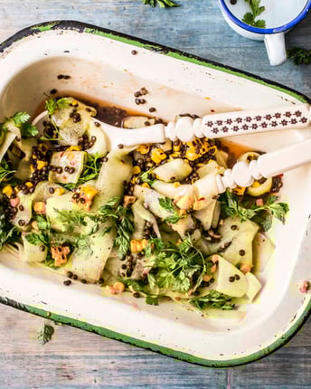Salat mit Mais, Gurken, Chili und Belugalinsen in einer kleinen Schale mit Salatbesteck.