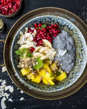 Chiapudding mit Mango, Granatapfel und Banane in einer Schüssel auf einem orientalischen Tablett.