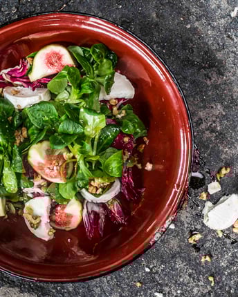 Blattsalat mit Feigen und Ziegenkäse in einer Schale mit Nüssen von oben