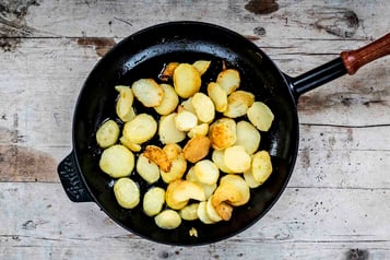 Kartoffelscheiben in schwarzer Pfanne braten