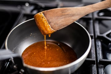 Karamellsauce in einem beschichtetem Topf mit einem Pfannenwender.