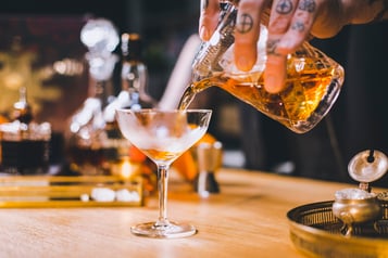 Tipperary Cocktail wird mit einem Strainer in eine Cocktailschale abgeseiht.