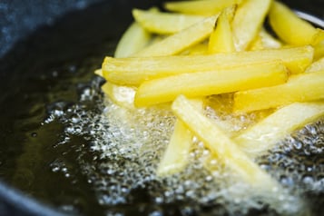 Pommes werden in heißem Öl in einem Topf frittiert