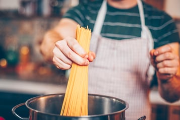 Spaghetti werden in Topf gegeben