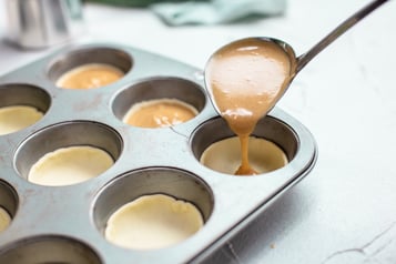 Baileys Füllung wird mit einer Suppenkelle in die Muffinmulden gegeben.