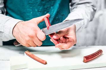Eine Rhabarberstange wird mit einem Messer eingeritzt.