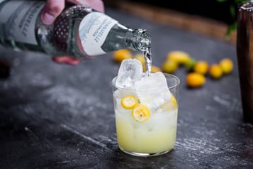 Der Kumquat Mocktail wird mit Mineralwasser aufgefüllt.