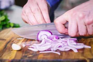 Zwiebeln werden für penne mit Artischocken und Weißwein geschnitten