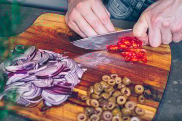 Zutaten für Bruschetta Salsiccia werden auf Holzbrett geschnitten