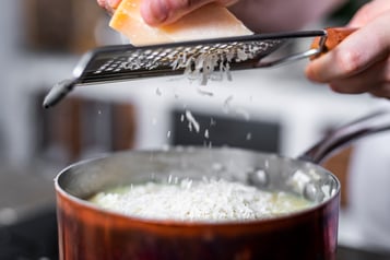 Parmesan wird über das Risotto gerieben