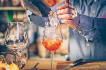 Hände geben mit Eisschaufel Eiswürfel in einer Drink-Glas
