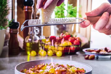 Pecorino mit Reibe über bunte Tomaten reiben