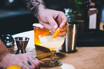 Die Orangenzeste in den Drink geben.