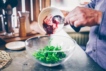 Rucola mit Himbeerkonfitüre in einer Schüssel marinieren.