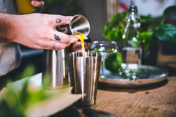 Ananassaft wird mit einem Jigger in den Cocktailshaker geben für einen Hawaiian Cocktail.