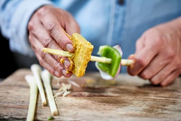 Lupinenfilets abwechselnd mit Paprika, Ananas und Zweibeln auf das Zitronengras spießen.