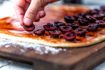 Hefeschneckenteig mit halbierten Sauerkirschen auf der Sauerkirschfüllung einzeln belegen.