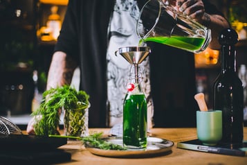 Dill-Sirup wird durch einen Trichter in eine Glasflasche gefüllt.