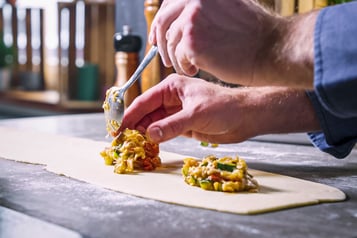 Füllung für vegetarische Mini-Calzoni wird auf Teig verteilt