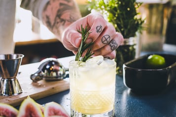 Drink mit einem Zweig Rosmarin dekorieren und anschließend mit einer halben Feige.