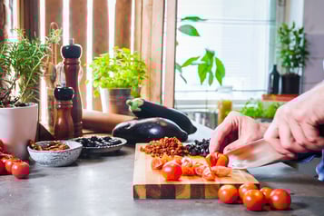 Kirschtomaten werden mit einem Messer auf Schneidebrett geschnitten