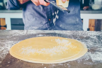 Pizzateig-mit-Parmesan-bestreuen