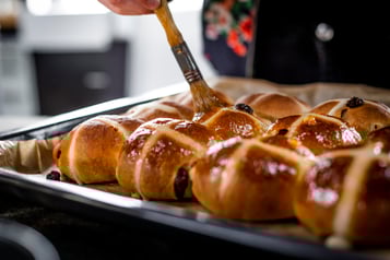 Die frisch gebackenen Hot Cross Buns werden mit Konfitüre eingepinselt.