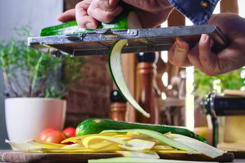 Zucchini werden für Gemüselasagne in Streifen geschnitten