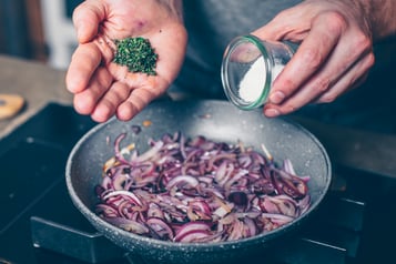 Zwiebeln für Bruschetta Salsiccia werden karamellisiert und Gewürze werden in Pfanne gegeben