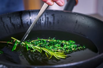 Thymian und Rosmarin werden für vegetarische Mini-Calzoni durch Öl gezogen