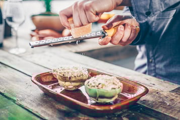 Gefüllte Artischockenhälften werden mit Parmesan bestreut, bevor sie gegrillt werden.