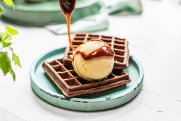 Schokowaffeln auf türkisem Teller mit Vanilleeis und Karamell-Sauce.