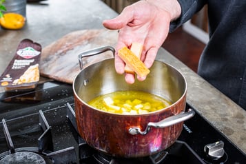 Parmesanrinde in einen Topf mit Brühe geben